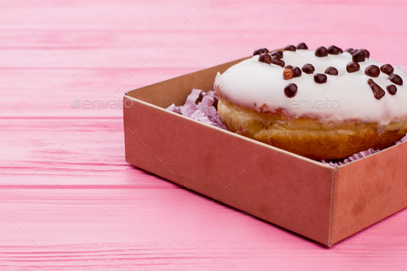 Box with donut on color background.