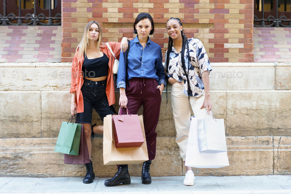 Stylish young diverse female friends standing on street after shopping - Stock Photo - Images