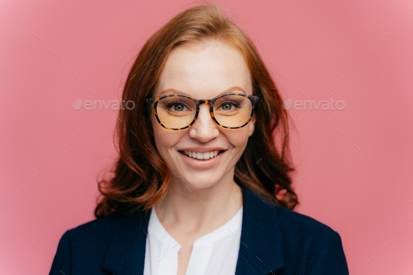Beautiful redhead gorgeous woman in optical glasses, has toothy smile, dressed in elegant clothes - Stock Photo - Images