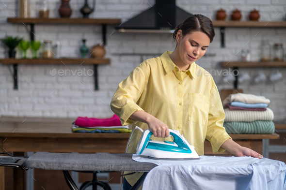 Concentrated housewife ironing wrinkled clothes on the ironing-board