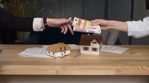 Female Clients Hands Giving Money to her Female Realtor alt