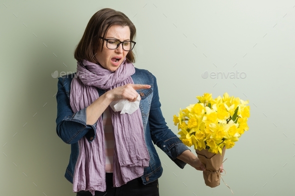 Spring allergy to pollen. Woman with bouquet of yellow flowers is going to sneeze.