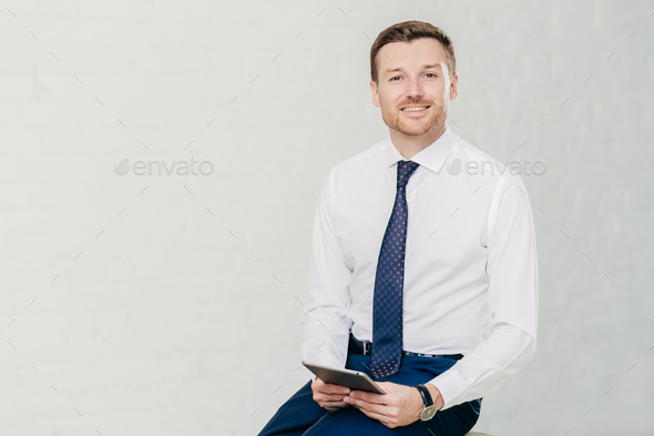 Intelligent lawyer in elegant clothes, holds digital tablet, spends free time in office