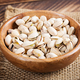 Pistachio nuts in shell  in bowl on wooden background. - PhotoDune Item for Sale