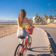 Attractive young woman riding bike near beach with palm trees - PhotoDune Item for Sale