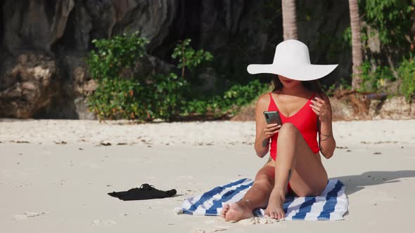 Woman Sitting On Beach Taking Selfie With Smartphone alt