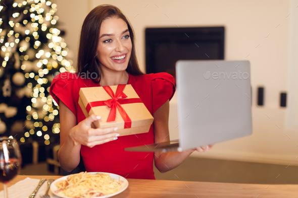 Woman showing gify box during virtual date on laptop - Stock Photo - Images