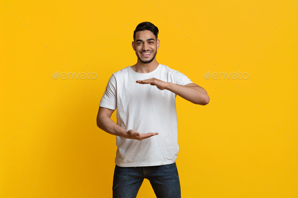Positive muslim guy holding something invisible in his hands - Stock Photo - Images