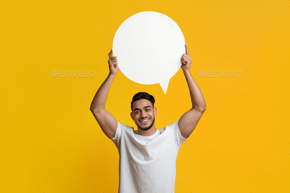 Middle eastern man holding blank speech bubble on yellow