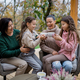 Two happy sisters with mother and grandmother sitting and drinking tea outdoors in patio in autumn - PhotoDune Item for Sale