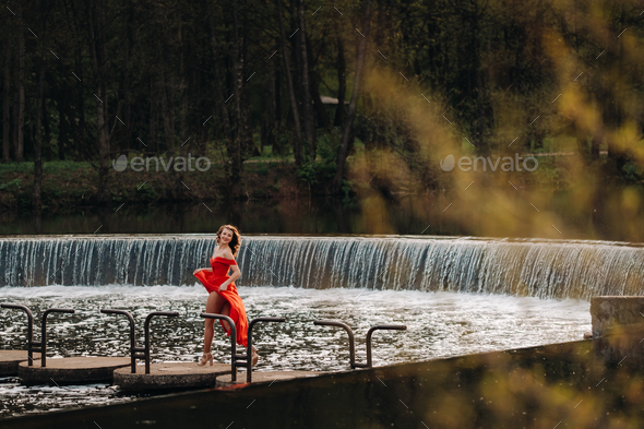girl in a long red dress near the lake in the Park at sunset Stock ...