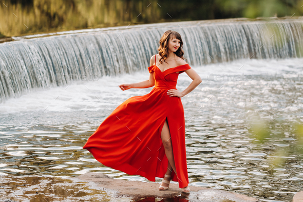 girl in a long red dress near the lake in the Park at sunset Stock ...