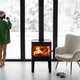 Woman with cup by the fireplace at house on nature in winter - PhotoDune Item for Sale