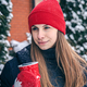 A young woman drinks a hot drink from a red thermal cup in winter. - PhotoDune Item for Sale