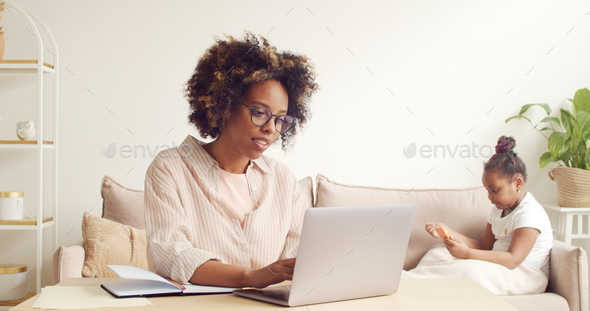 Attractive african american woman works online at home to support child