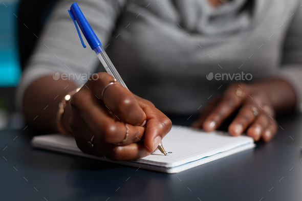 Close up of hand holding pen to write on textbook file