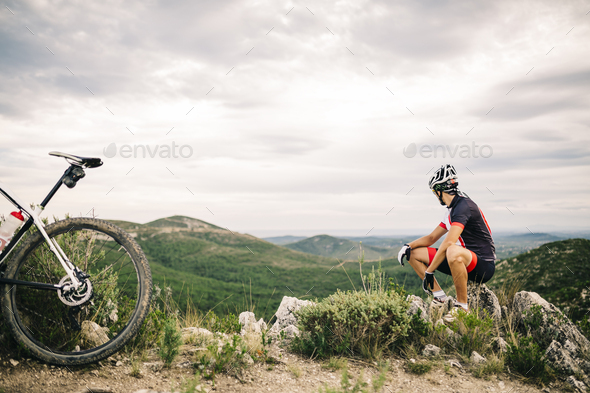 Spain, Tarragona, Mountain biker having a break in extreme terrain - Stock Photo - Images