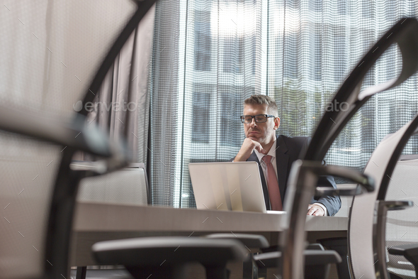 Poland, Warzawa, businessman sitting at conference table in hotel using laptop - Stock Photo - Images