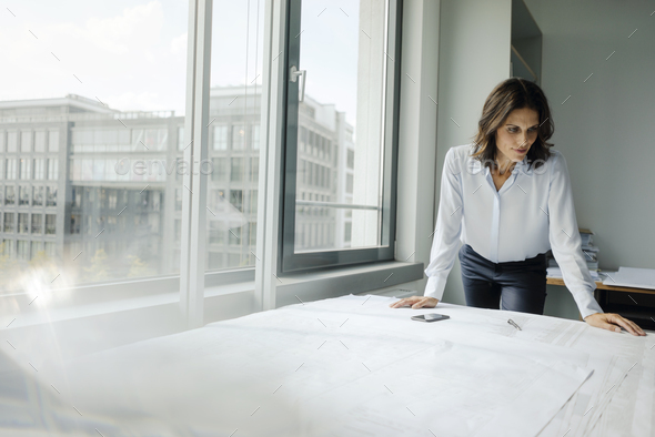 Businesswoman working in office, looking at blueprints - Stock Photo - Images