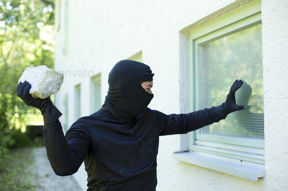 Burglar with stone breaking window