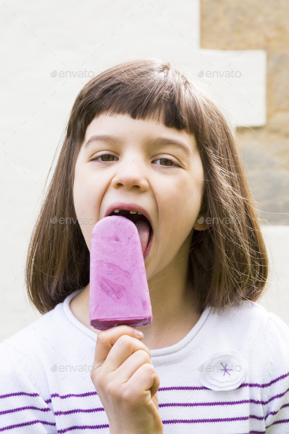 Portrait of little girl with yoghurt blueberry ice lolly Stock Photo by