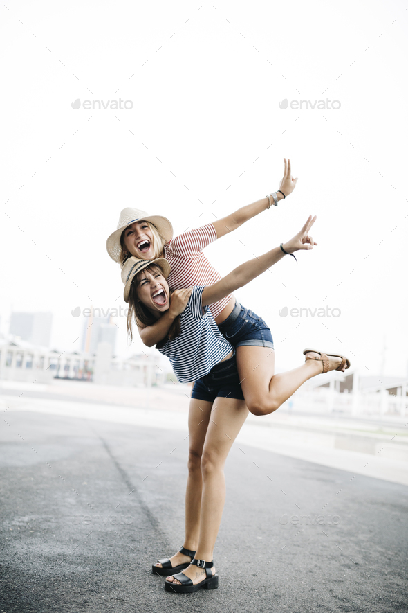 Girl giving her friend a piggyback ride stock photo