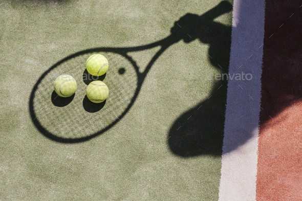 Shadow of a tennis player with balls and racket on court