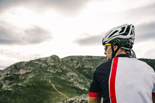 Spain, Tarragona, Mountain biker in extreme terrain, looking at landscape - Stock Photo - Images