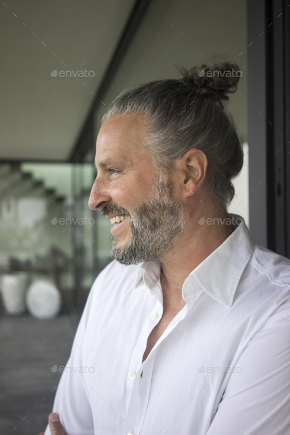 Portrait of happy mature man with hair bun