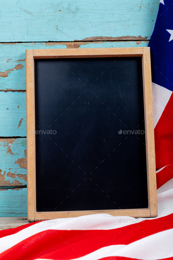 Overhead view of blank writing slate with copy space by usa flag on blue wooden table