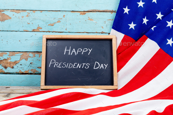 Happy presidents day text on writing slate with america flag on blue wooden table with copy space