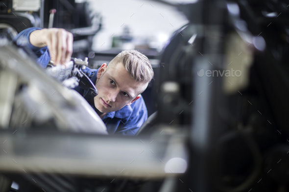 Young man adjusting a machine in a printing company