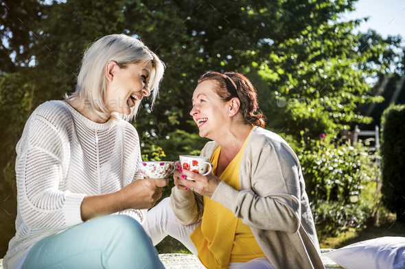 Happy mature women in garden with coffee cups