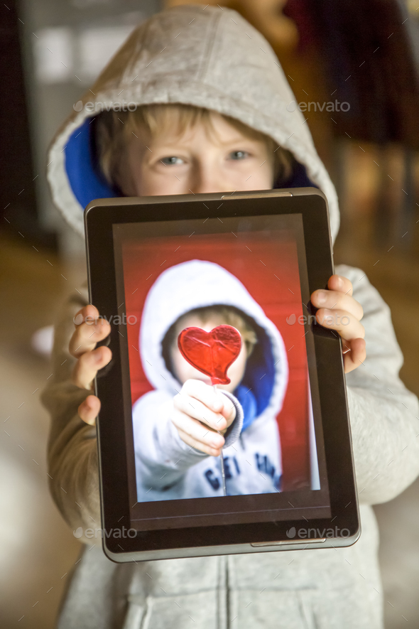 Boy showing digital tablet with photography of himself