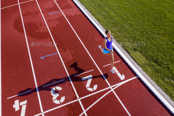 Aerial view of a running young female athlete on a tartan track crossing finishing line