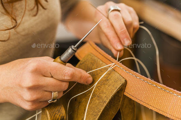 Woman sewing elastic fabric rubber band using lacing pony and awl