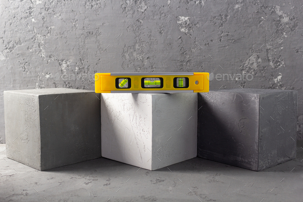 Concrete cube and construction level on brick at abstract background - Stock Photo - Images