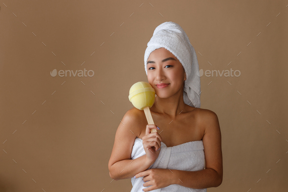 Smiling Asian woman holding lollipop bath sponge