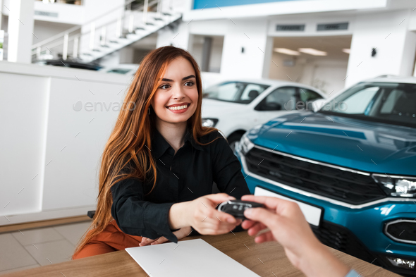 Auto showroom salesman gives the female client the key to her new car