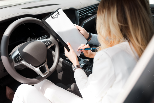 Woman signs a deal with a car dealership about buying, leasing car - Stock Photo - Images