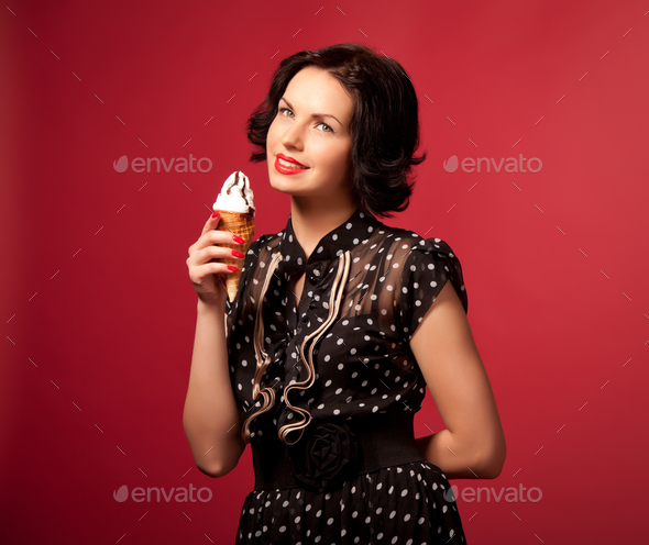 Young woman in black vintage dress standing eating ice cream over red background
