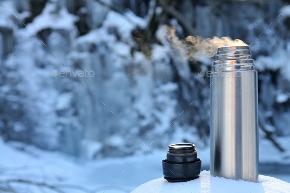 Thermos with a hot drink on mountain waterfall Stock Photo by YouraPechkin