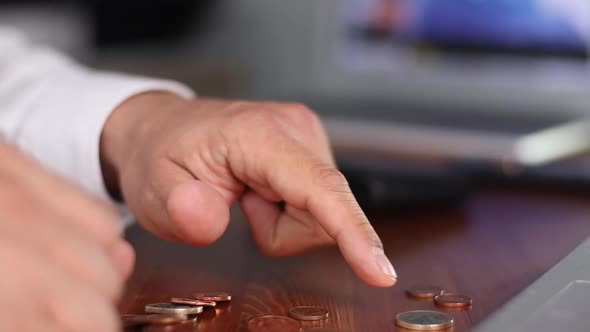 Businessman Counting Coins on the Table
