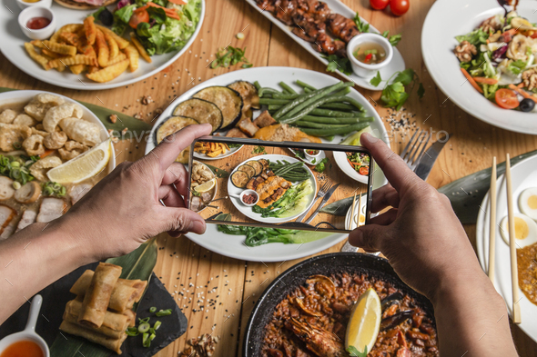 A man takes a photo of food on his smartphone at a Filipino restaurant. He shares your lifestyle