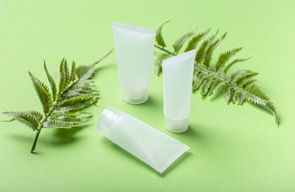 Skincare organic beauty product bottles, plant leaves on green background