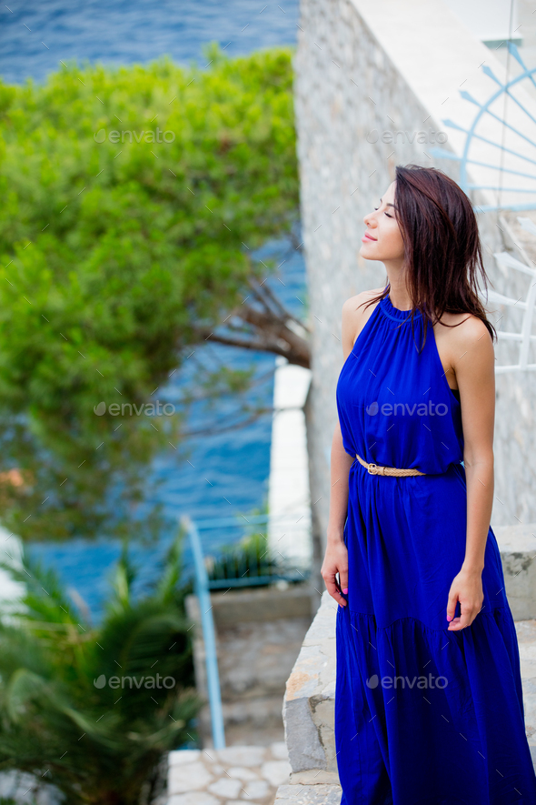 photo of beautiful young woman standing on the stairs near the house in Greece