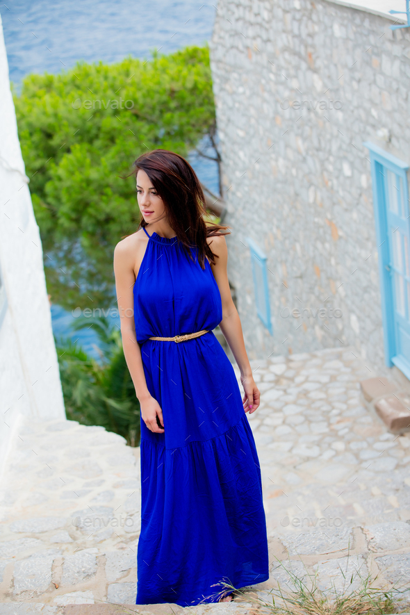 photo of beautiful young woman standing on the stairs near the house in Greece