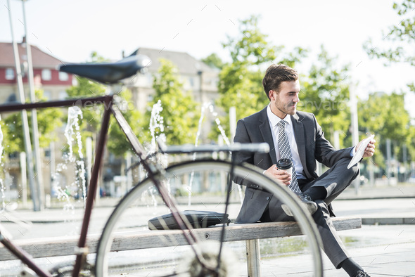 Young businessman sitting on bench using digital tablet - Stock Photo - Images
