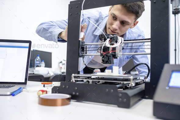 Student setting up 3D printer, using laptop