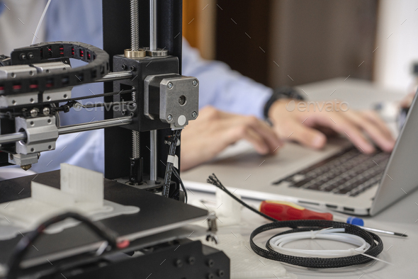 Student setting up 3D printer,using laptop, close up